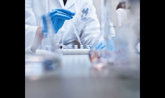 Lab technician conducting testing with vials and dropper